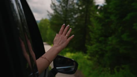 woman's hand out of car window enjoying scenic drive
