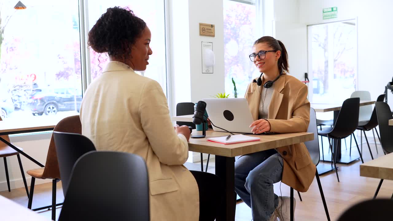 Two women recording a podcast interview indoors