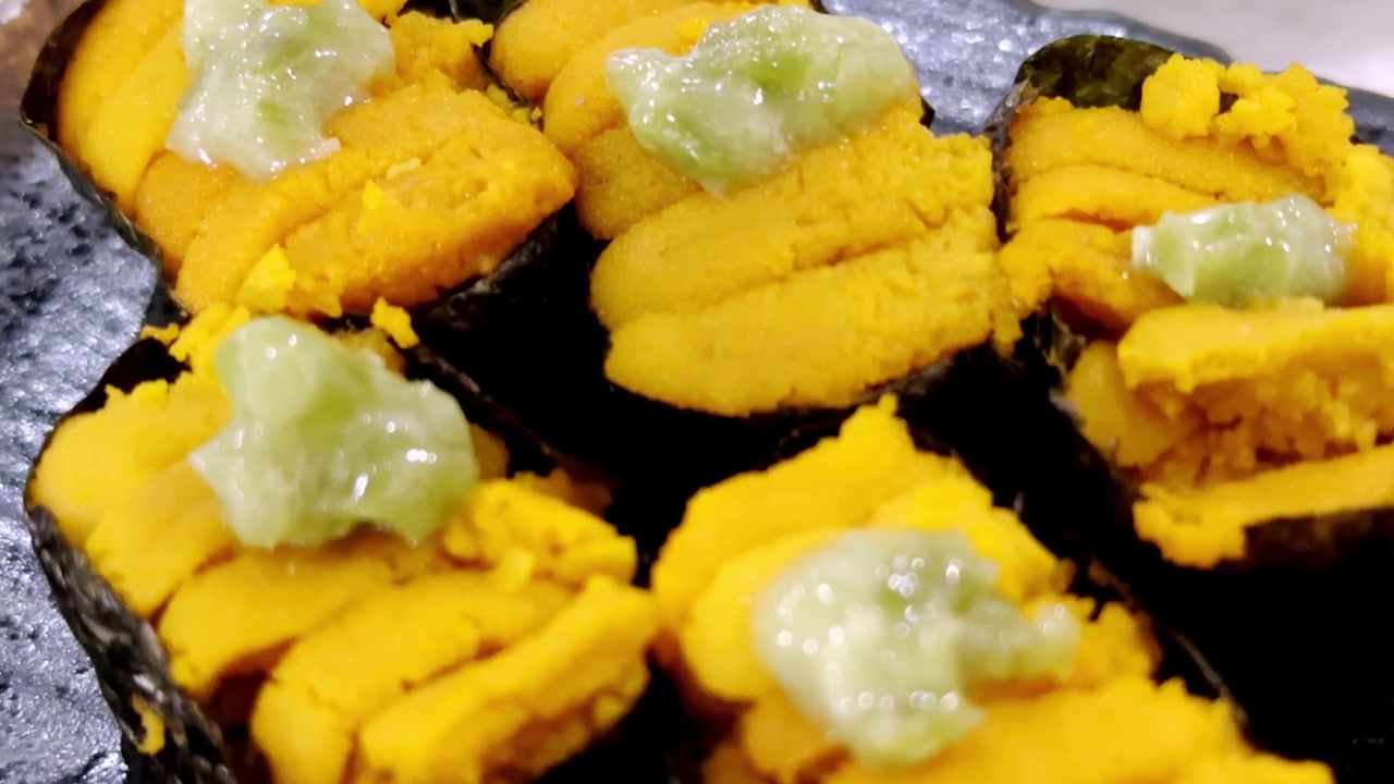Primo piano di sushi uni fresco con riccio di mare di alta qualità servito su riso giapponese condito, che evidenzia una consistenza ricca e una presentazione gourmet autentica
