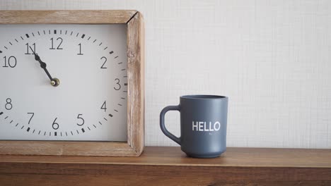 taza gris y reloj en un estante de madera