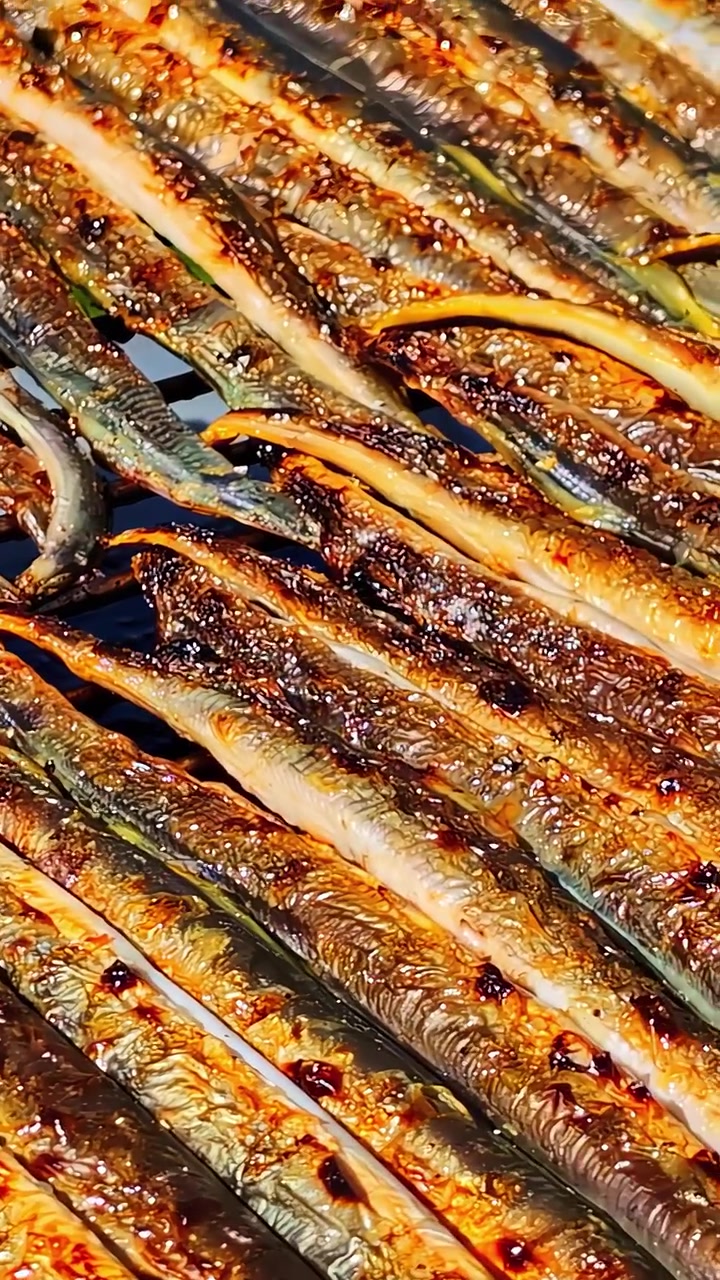 Autentico primo piano cinematografico di piccoli pesci che grigliano su un barbecue. Ideale per contenuti culinari, sulla sostenibilità e sullo stile di vita sano.