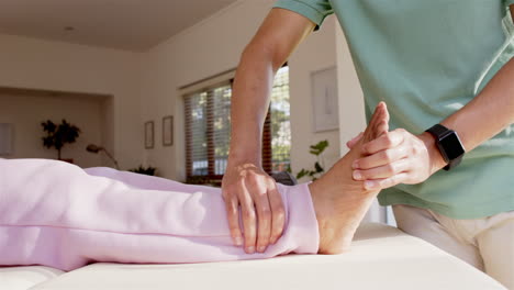 physiotherapist treating senior woman's leg, focusing on ankle and foot therapy