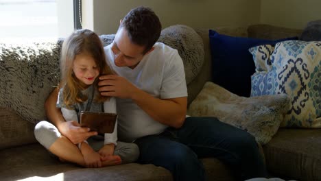 Father-and-daughter-using-digital-tablet-in-living-room-4k