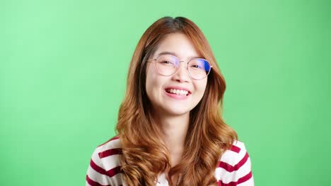 happy young asian woman in striped t-shirt wearing eyeglasses looking at camera and smiling joyfully, green screen background