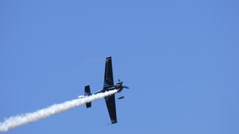 aerobatic propeller airplane flying airshow with trailing smoke slomo