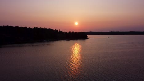 bright sun setting down behind silhouette of stockholm archipelago islands, aerial view