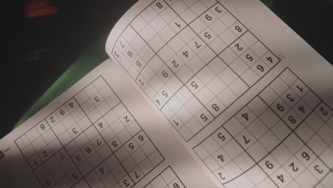 soft light falls on open page of sudoku puzzle book, lifestyle concept