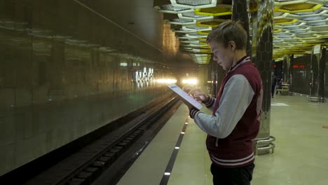 teenager using tablet at a busy subway station