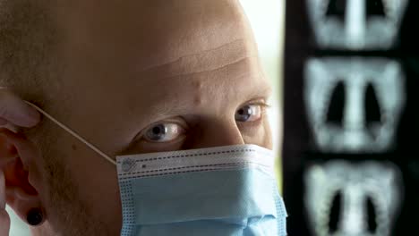 Caucasian-doctor-with-gray-eyes-putting-on-Surgical-mask-and-Protective-glasses