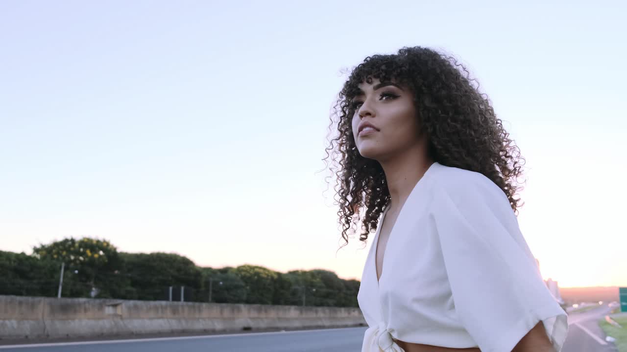 Woman hitchhiking on the highway at sunset