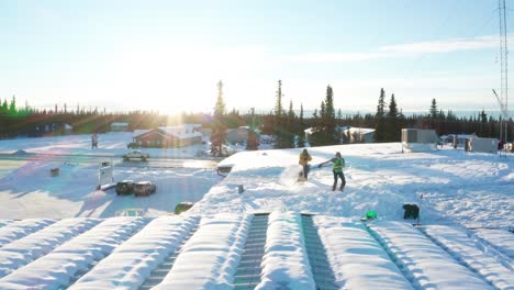 two men shoveling the snow off the roof of a local business warehouse in soldotna, alaska