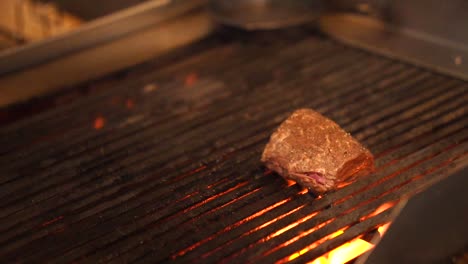 Steak-Piece-Being-Tapped-By-Hand-On-BBQ-Grill-With-Flames