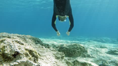 a diver swimming through the translucent beach waters of paralia emplisi during the day in greece, europe