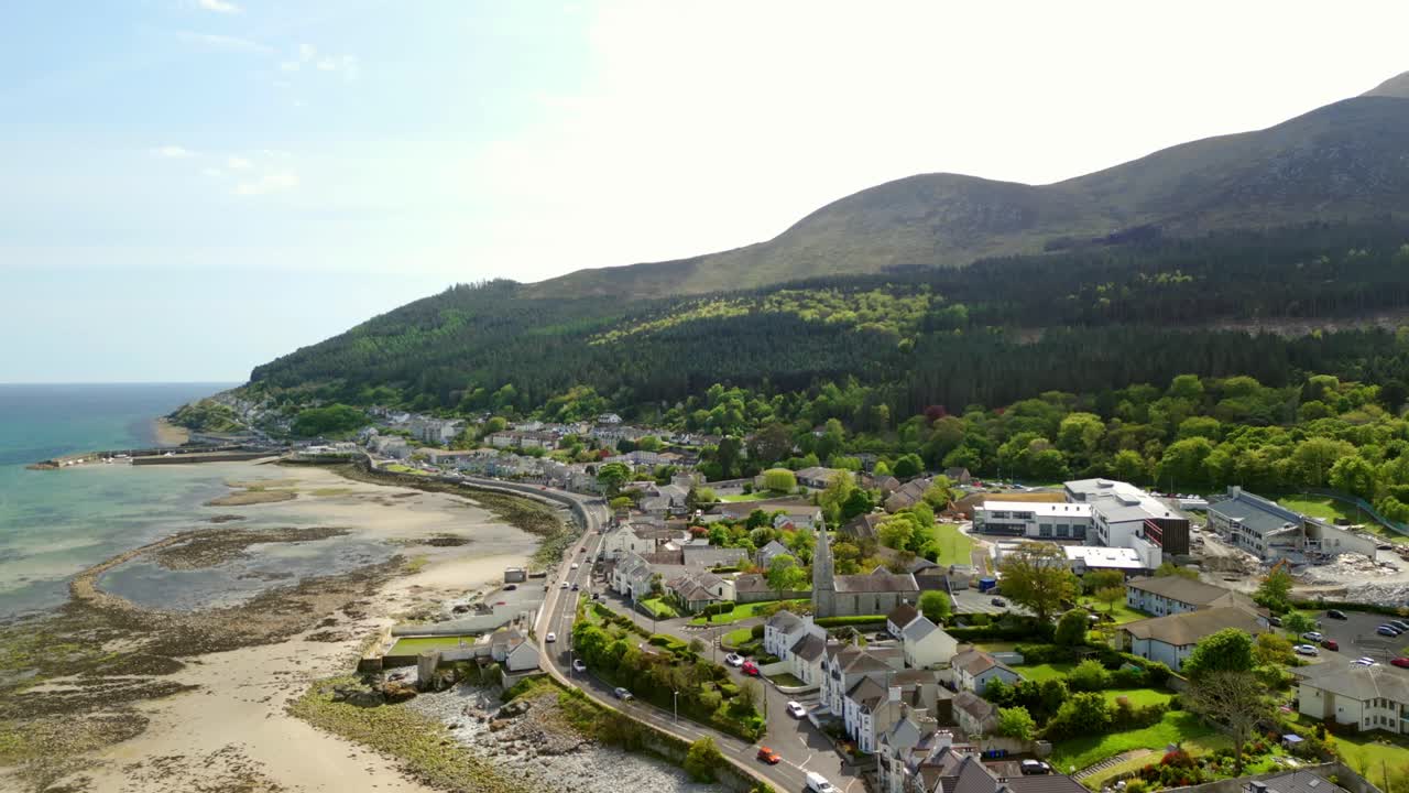 Advancing aerial video of the Mourne Mountains and the beach in Newcastle, County Down in Northern Ireland, UK on a bright and sunny day. Filmed in 4K, 60fps and with Rec709 Color.