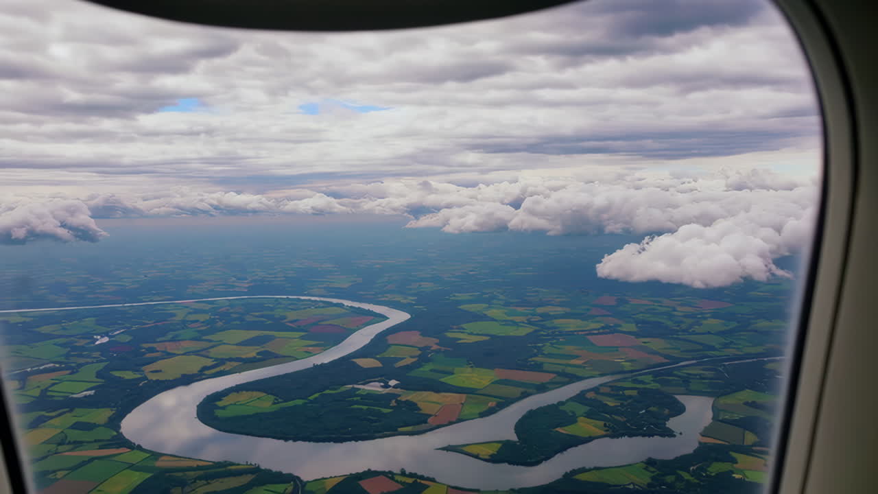 Aerial View of a Winding River and Agricultural Fields from an Airplane Window