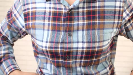 man buttoning a plaid shirt