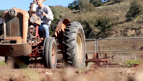 rancher driving tractor with harrow plowing field rack focus to tractor