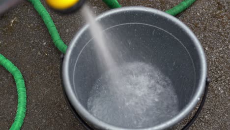 agua dulce de una manguera que rocía en un balde derrochador