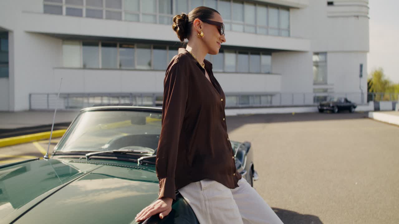Donna elegante in posa accanto a un'auto decappottabile classica verde