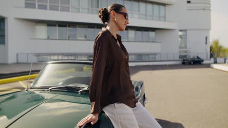stylish woman posing beside a classic green convertible car