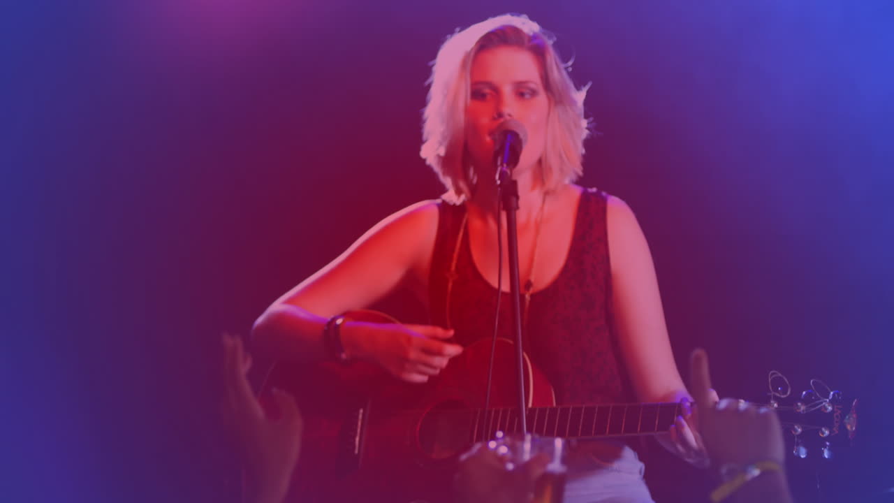 콘서트에서 기타를 연주하고 노래하는 백인 여성 가수에 대한 빛의 점의 애니메이션