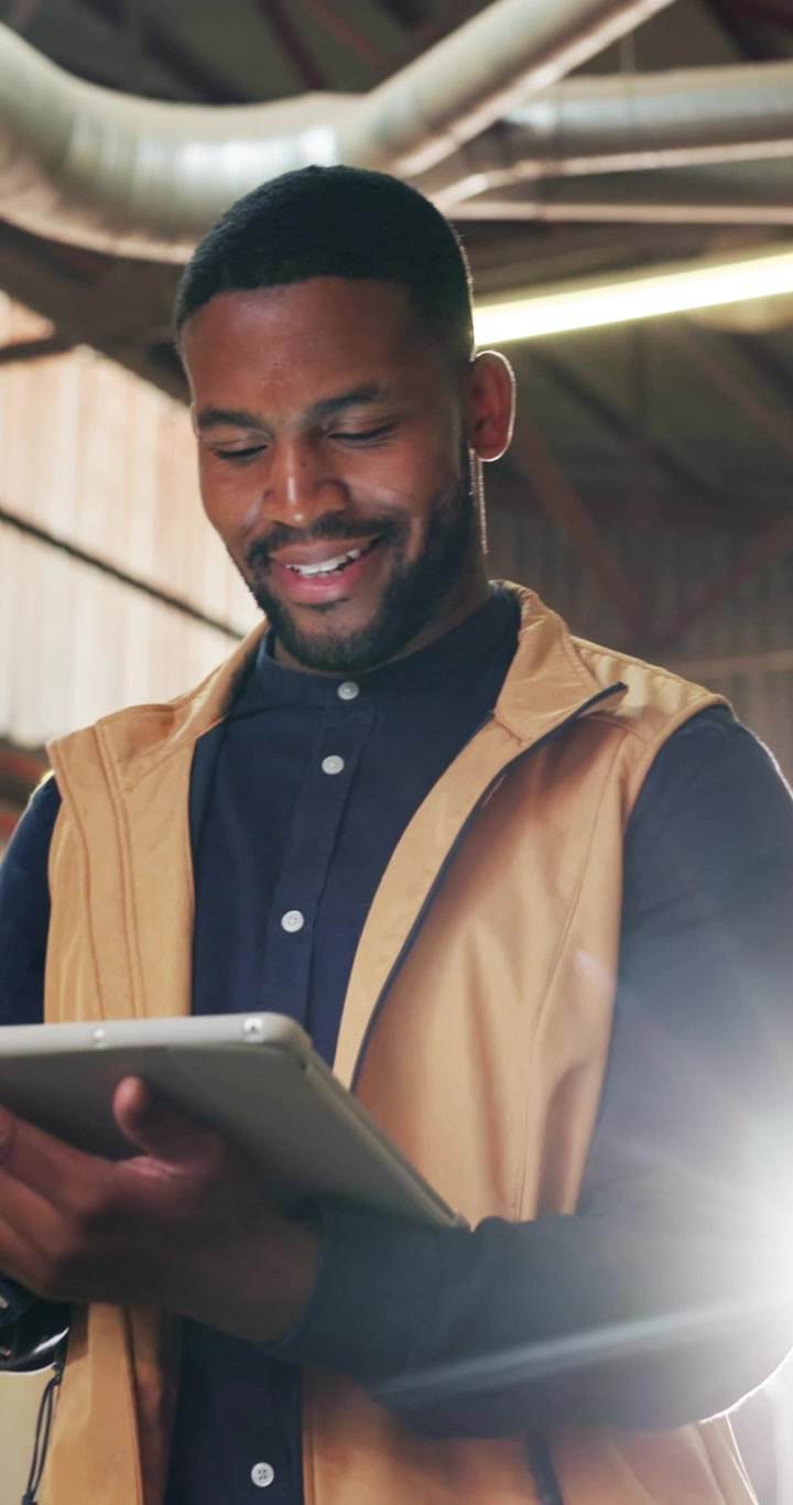 Young Man Using Tablet in Industrial Warehouse Setting