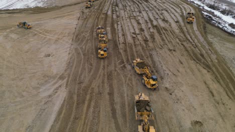 wheel tractor scrappers work in a construction site to level out and grade an area for a new housing development as seen from an aerial drone vantage point