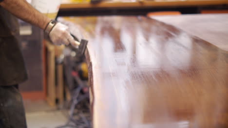 un carpintero profesional en su taller de carpintería, termina una mesa de madera natural hecha a medida con una capa de barniz.