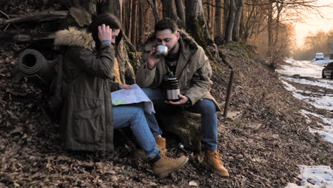 una pareja caucásica bebiendo té caliente en un bosque.