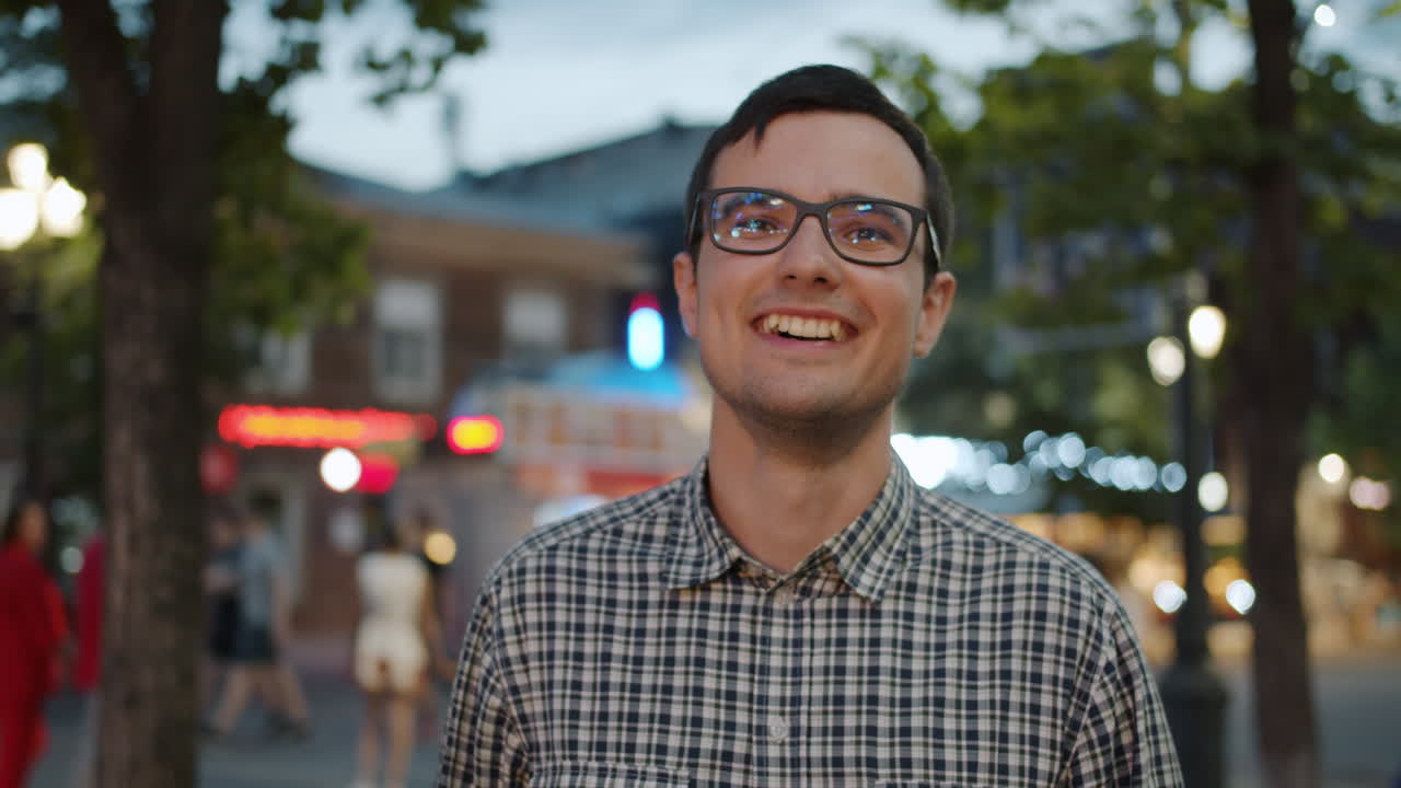 Smiling Man in Glasses on City Street at Night