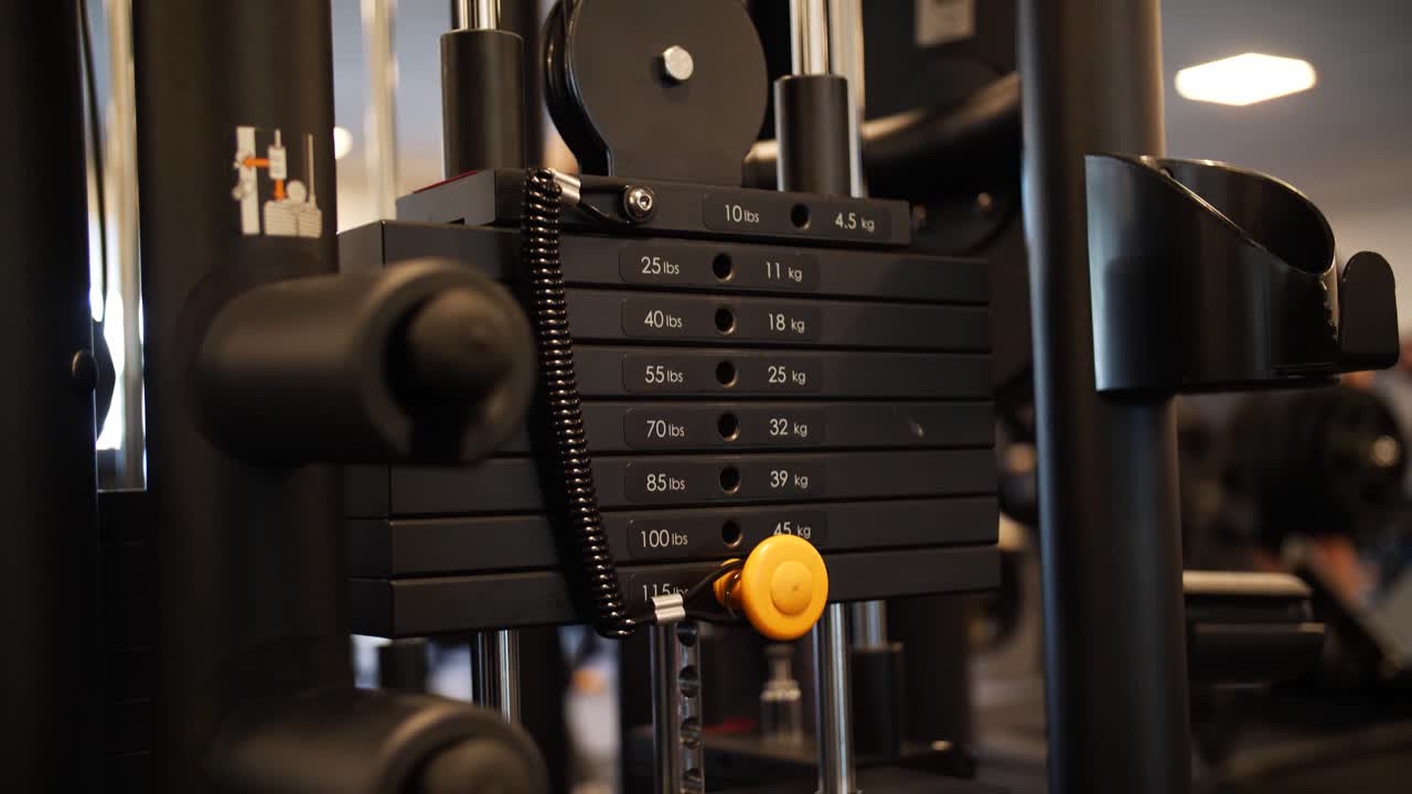 Slow motion close-up of a gym machine in action, emphasizing the movement of weights up and down