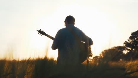 Músico-En-El-Campo-Durante-La-Puesta-De-Sol-Tocando-La-Guitarra.