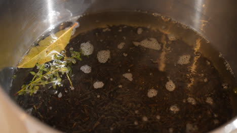 wilde rice heating up in a pan on the stove and seasoned with rosemary and a basil leaf - overhead view