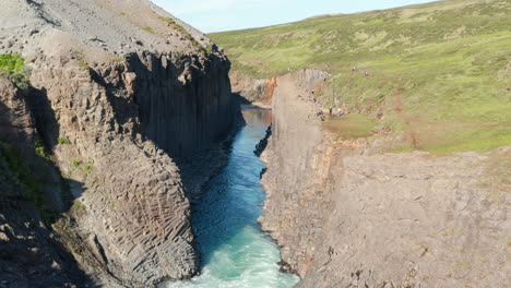 Aerial-view-of-Jokulsa-river-flowing-through-columns-of-volcanic-basalt-formations-in-Stuolagil-canyon-in-Iceland.-Drone-view-of-glacier-water-river-streaming-in-Vatnajokull-national-park