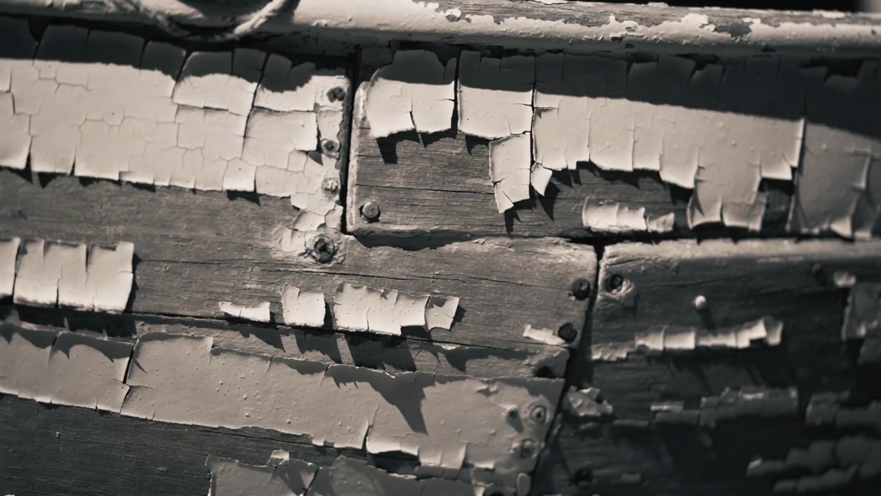 Panning camera across weathered painted panel outside, showing rivets and curled flakes for texture