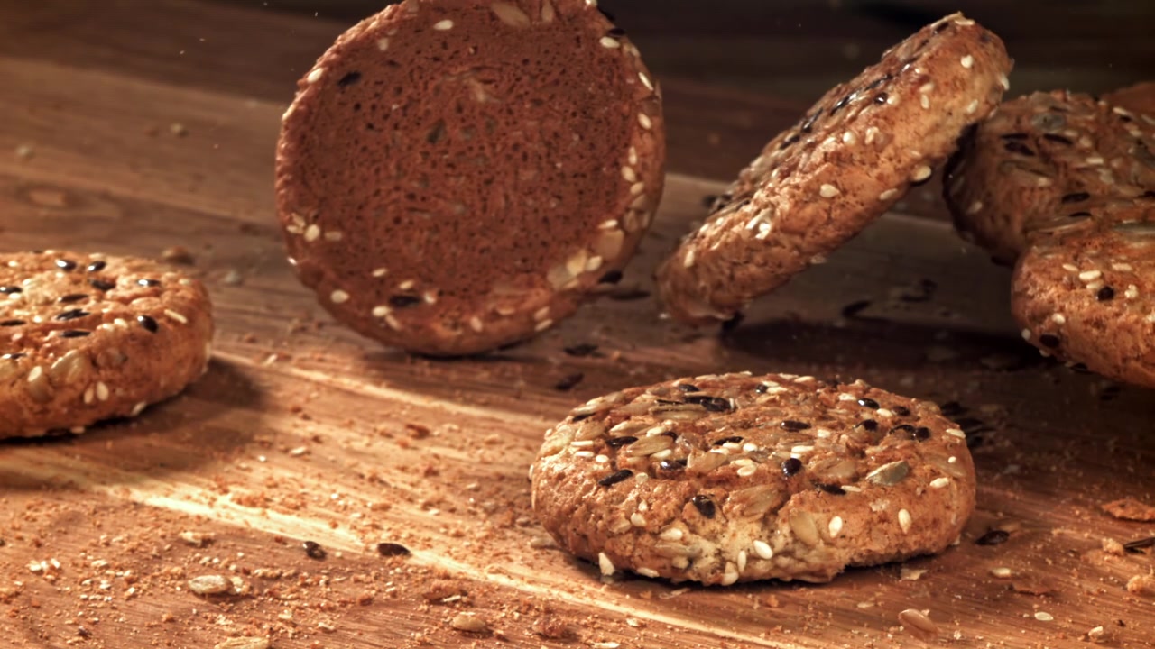 Deliciosos Biscoitos de Sementes Caindo em Câmera Lenta em Superfície de Madeira