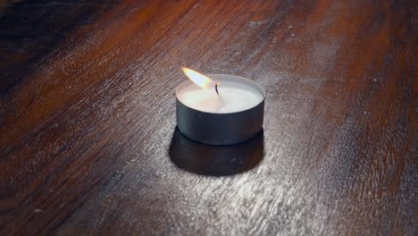 burning single tea light candle is blown out, smoke rises from wick