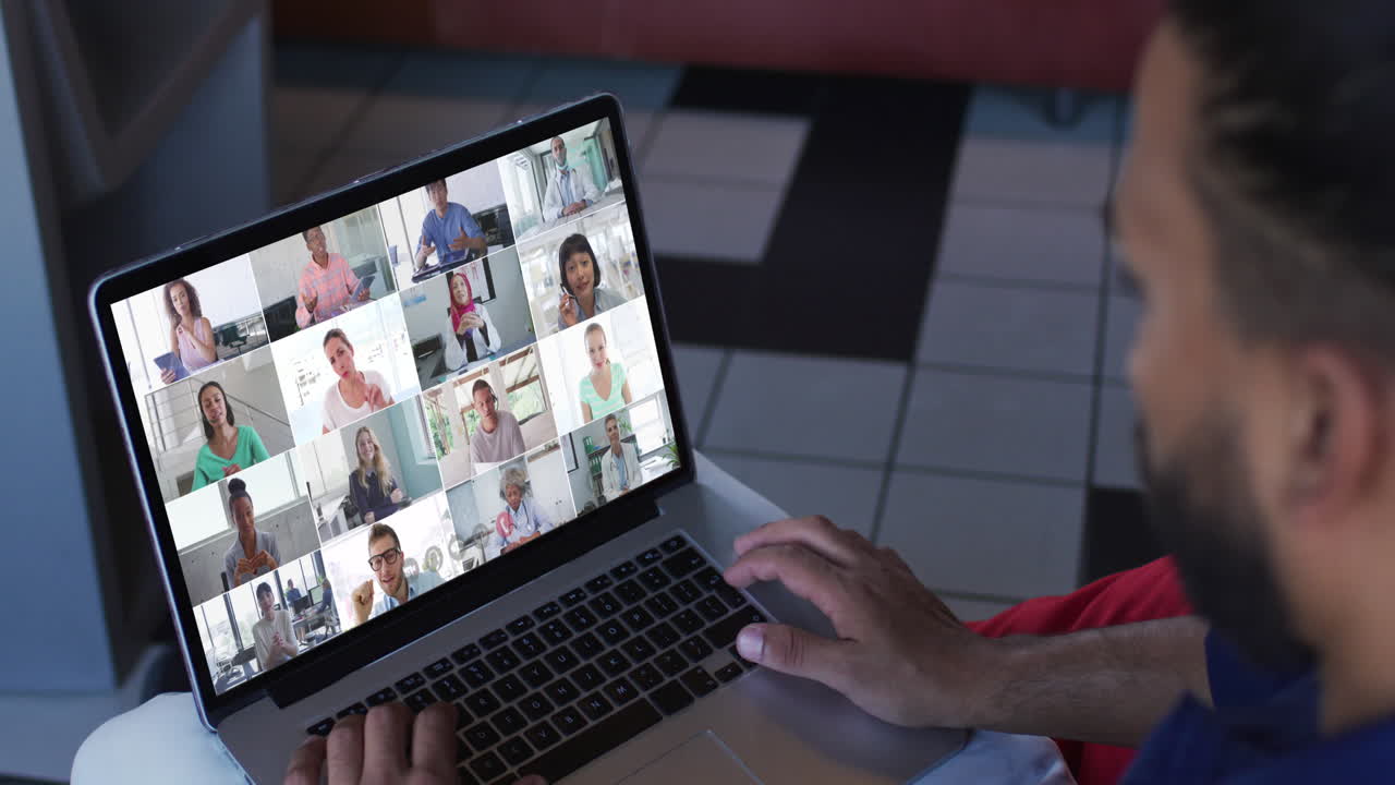 African american man having a video conference with office colleagues on laptop at home