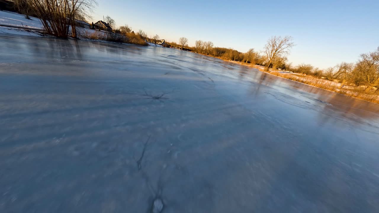 drone rápido volando sobre un estanque congelado en michigan durante la puesta de sol