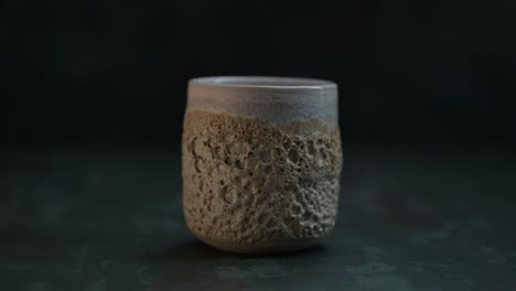 Purring-a-water-into-a-ceramic-glass-with-volcano-texture-on-the-dark-background