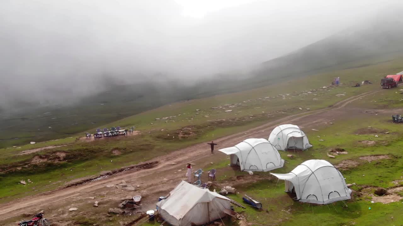 un video aéreo tomado por un dron muestra el valle de babuino neelum top en pakistán, que está envuelto en niebla y tiene cinco tiendas de campaña con numerosos ocupantes