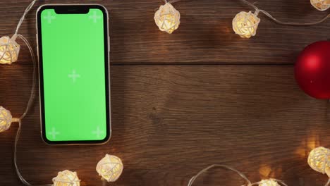 winter holidays present box and smartphone green screen on wooden desk garland