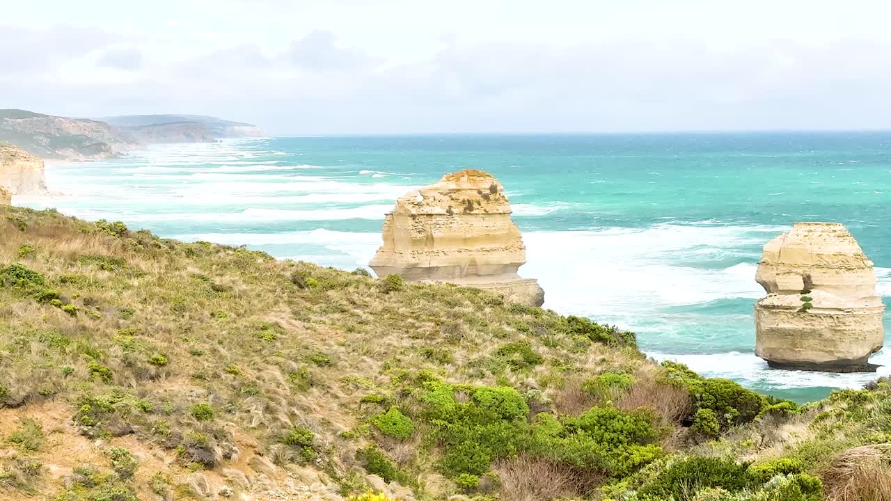 Panoramic view of the Twelve Apostles with vibrant ocean hues and rugged cliffs under soft daylight