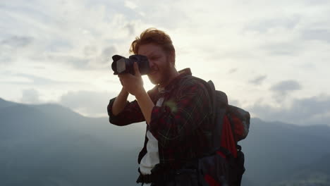 nature photographer shooting mountains. closeup focused man hold camera on hike.