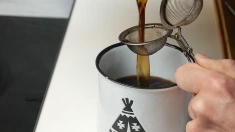 filtering home-made chaga mushroom tea in a cup