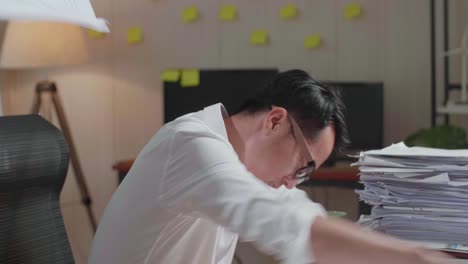 close up of asian man having headache while working hard with documents at the office