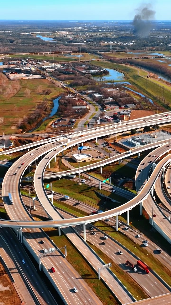 Lalu lintas transportasi di kota metropolitan modern. Pemandangan persimpangan jalan raya dengan banyak jalan dan mobil di Dallas, Texas, AS. Perspektif udara. Video vertikal