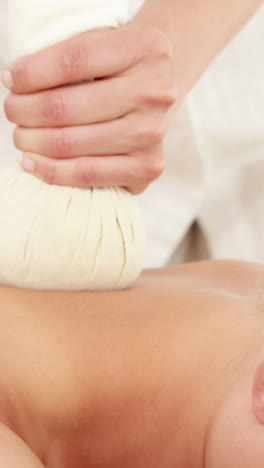 mujer disfrutando de un masaje de compresa de hierbas