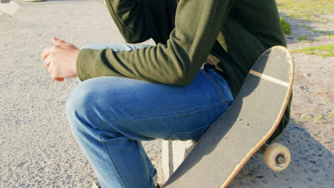 side view of young caucasian man talking on mobile phone while sitting on the pavement 4k