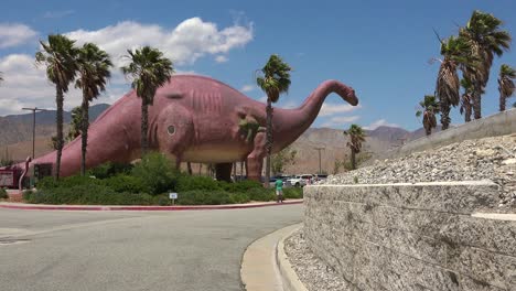 cabazon california 1 근처의 모하비 사막에 있는 길가 명소로 방문객들 위에 거대한 인공 공룡이 어렴풋이 보입니다.